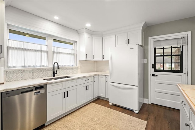 1924 Cammie Ave, Metairie, LA 70003 - kitchen with stainless steel dishwasher, freestanding refrigerator, a sink, dark wood-type flooring, and white cabinetry