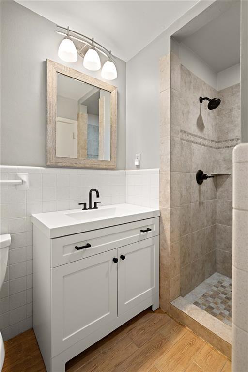 1924 Cammie Ave, Metairie, LA 70003 - bathroom featuring tile walls, toilet, tiled shower, vanity, and wood finished floors