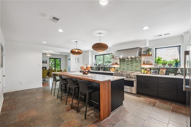 788 Amethyst St, New Orleans, LA 70124 - kitchen featuring high end stainless steel range, wall chimney range hood, a center island, a kitchen breakfast bar, and healthy amount of natural light