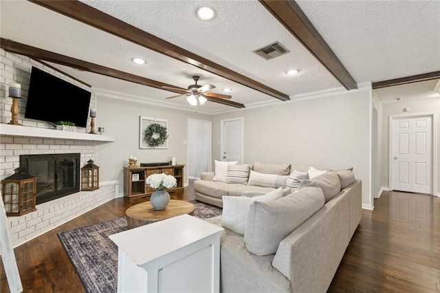 4212 Pommard Dr, Kenner, LA 70065 - living room featuring a textured ceiling, beam ceiling, dark wood-type flooring, a ceiling fan, and a fireplace