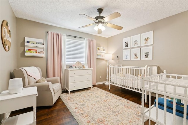 4212 Pommard Dr, Kenner, LA 70065 - bedroom with a crib, dark wood finished floors, a textured ceiling, a ceiling fan, and baseboards