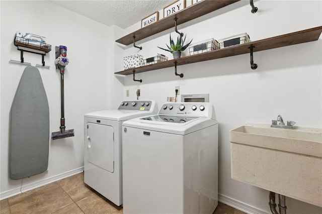 4212 Pommard Dr, Kenner, LA 70065 - laundry area with washing machine and clothes dryer, baseboards, light tile patterned floors, and a textured ceiling