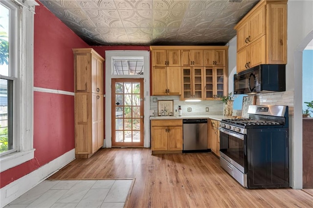 8301 Belfast St Unit 8303, New Orleans, LA 70118 - kitchen with appliances with stainless steel finishes, an ornate ceiling, tasteful backsplash, light countertops, and light wood-type flooring