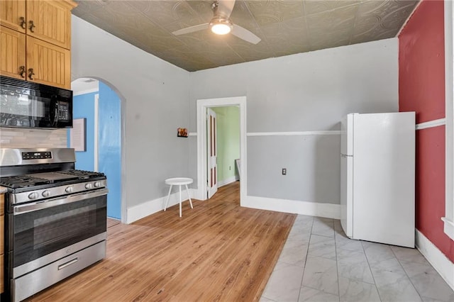 8301 Belfast St Unit 8303, New Orleans, LA 70118 - kitchen with freestanding refrigerator, black microwave, gas range, arched walkways, and an ornate ceiling
