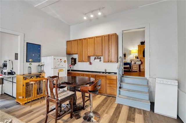 8301 Belfast St Unit 8303, New Orleans, LA 70118 - kitchen with freestanding refrigerator, light wood-style flooring, brown cabinets, and rail lighting