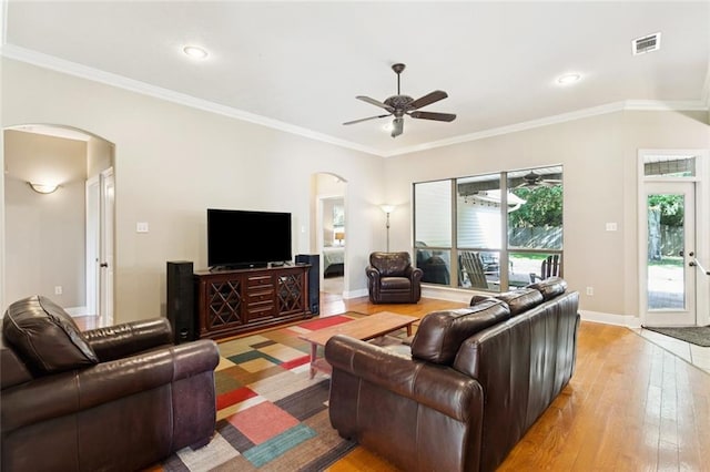1061 Tallow Tree Dr, Mandeville, LA 70448 - living room featuring arched walkways, ceiling fan, light wood-style flooring, crown molding, and baseboards