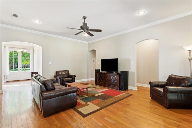 1061 Tallow Tree Dr, Mandeville, LA 70448 - living room featuring arched walkways, light wood-style floors, ornamental molding, ceiling fan, and baseboards