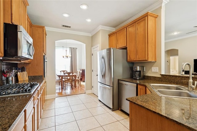 1061 Tallow Tree Dr, Mandeville, LA 70448 - kitchen featuring a sink, appliances with stainless steel finishes, arched walkways, brown cabinetry, and crown molding