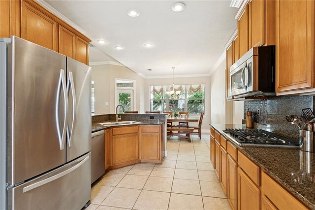 1061 Tallow Tree Dr, Mandeville, LA 70448 - kitchen with stainless steel appliances, a sink, ornamental molding, light tile patterned floors, and brown cabinetry
