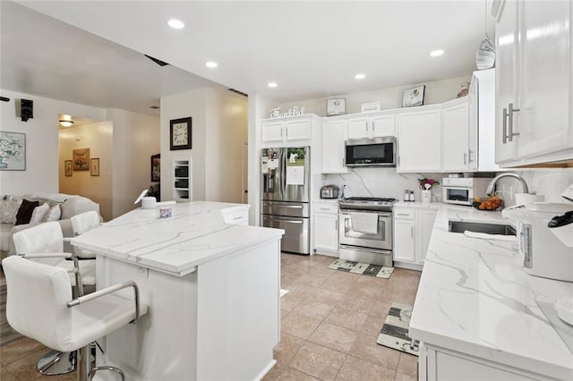 728 Fairfield Loop, Slidell, LA 70458 - kitchen featuring appliances with stainless steel finishes, a sink, a kitchen island, backsplash, and white cabinets