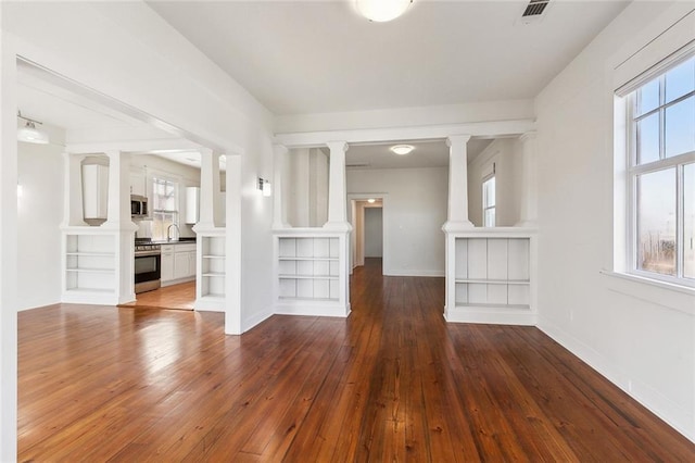 3019 Burdette St, New Orleans, LA 70125 - unfurnished living room featuring hardwood / wood-style floors, ornate columns, baseboards, a sink, and built in shelves