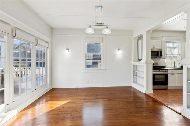3019 Burdette St, New Orleans, LA 70125 - unfurnished dining area with plenty of natural light, wood-type flooring, a sink, and ornate columns