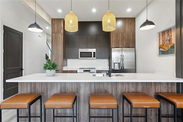 2404 Danneel St, New Orleans, LA 70113 - kitchen featuring stainless steel appliances, a sink, light countertops, modern cabinets, and decorative light fixtures