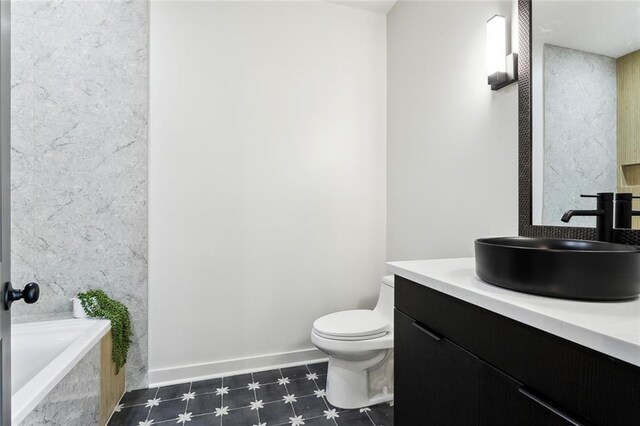 2404 Danneel St, New Orleans, LA 70113 - full bathroom with toilet, vanity, a tub to relax in, baseboards, and tile patterned floors