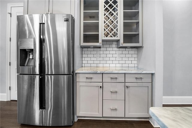 615 Newman Ave, Jefferson, LA 70121 - kitchen featuring stainless steel fridge with ice dispenser, decorative backsplash, glass insert cabinets, and baseboards