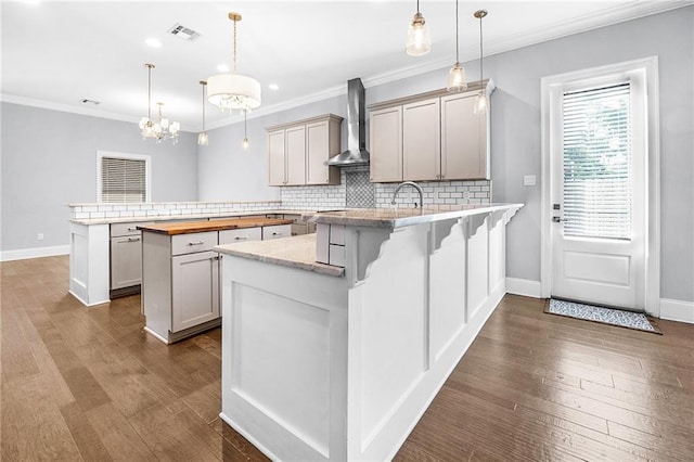 615 Newman Ave, Jefferson, LA 70121 - kitchen featuring a peninsula, wall chimney exhaust hood, decorative backsplash, baseboards, and crown molding