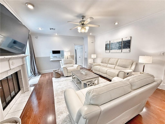 44 Stonebridge Ct, Mandeville, LA 70448 - living room featuring ceiling fan, light wood-type flooring, crown molding, a wainscoted wall, and a fireplace