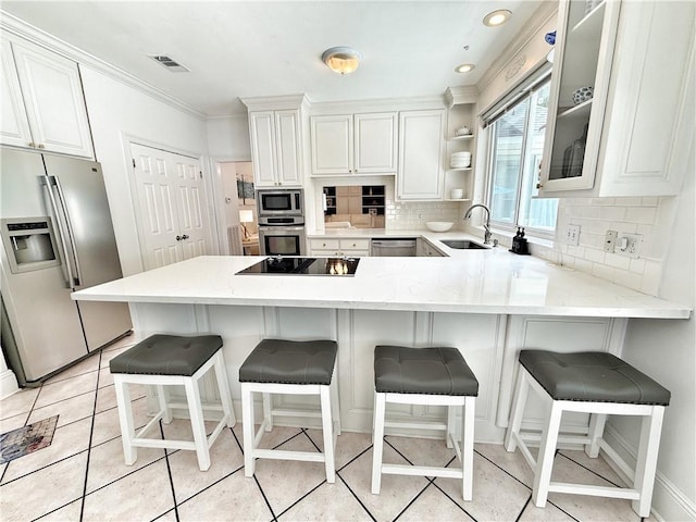44 Stonebridge Ct, Mandeville, LA 70448 - kitchen with stainless steel appliances, tasteful backsplash, a peninsula, white cabinets, and crown molding