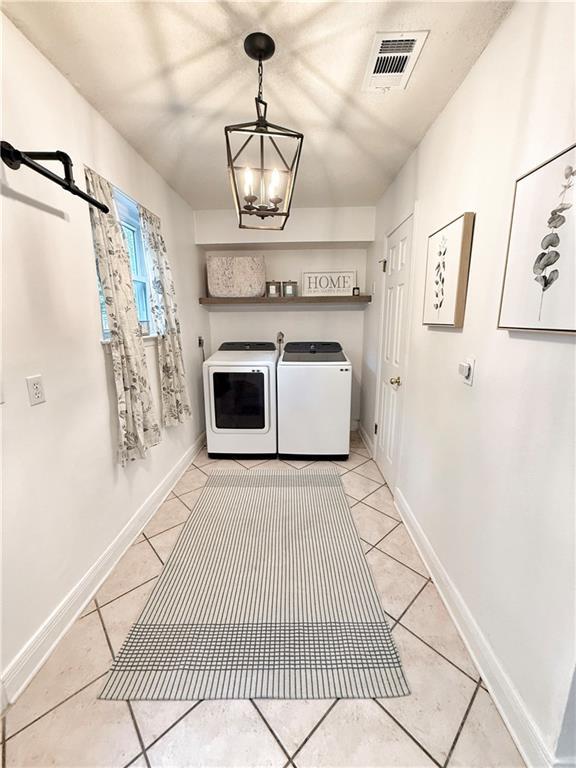 44 Stonebridge Ct, Mandeville, LA 70448 - laundry room featuring washing machine and clothes dryer, a chandelier, and light tile patterned floors