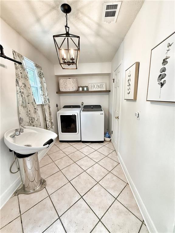 44 Stonebridge Ct, Mandeville, LA 70448 - laundry area featuring washer and clothes dryer, light tile patterned flooring, baseboards, and a chandelier