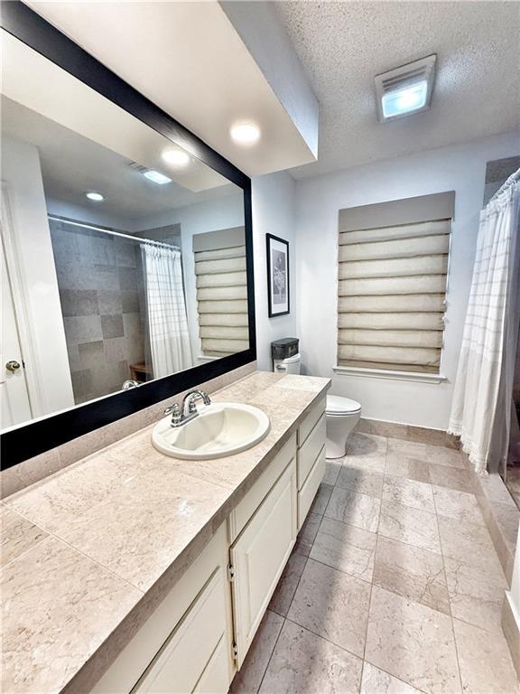 44 Stonebridge Ct, Mandeville, LA 70448 - bathroom featuring toilet, vanity, a shower with shower curtain, a textured ceiling, and baseboards