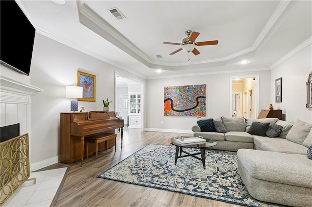 5714 Vicksburg St, New Orleans, LA 70124 - living area with a raised ceiling, ceiling fan, baseboards, light wood-type flooring, and crown molding