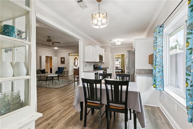 5714 Vicksburg St, New Orleans, LA 70124 - dining room featuring plenty of natural light, light wood-type flooring, a chandelier, crown molding, and baseboards