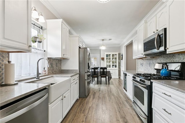 5714 Vicksburg St, New Orleans, LA 70124 - kitchen with stainless steel appliances, white cabinetry, light wood-style floors, crown molding, and backsplash