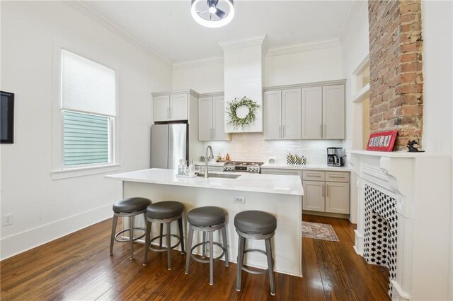 718 Monroe St, Gretna, LA 70053 - kitchen featuring freestanding refrigerator, a sink, a breakfast bar, decorative backsplash, and dark wood-style floors