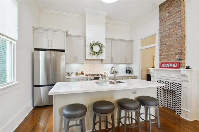 718 Monroe St, Gretna, LA 70053 - kitchen with appliances with stainless steel finishes, dark wood finished floors, decorative backsplash, a kitchen breakfast bar, and a center island with sink