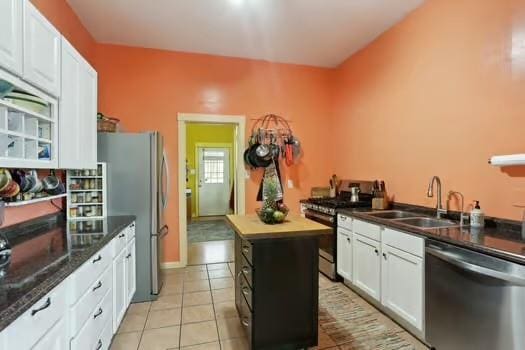 640 Lizardi St, New Orleans, LA 70117 - kitchen featuring appliances with stainless steel finishes, a sink, white cabinets, light tile patterned floors, and a center island