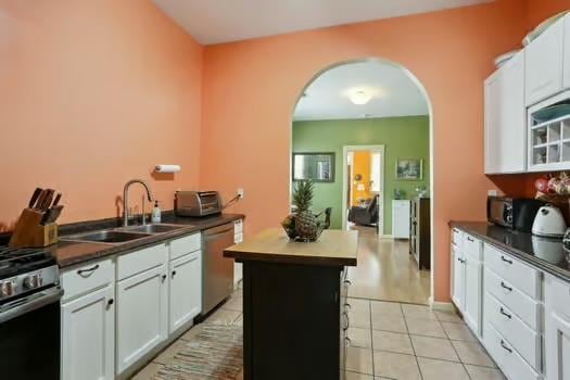640 Lizardi St, New Orleans, LA 70117 - kitchen with stainless steel appliances, a sink, arched walkways, dark countertops, and light tile patterned flooring