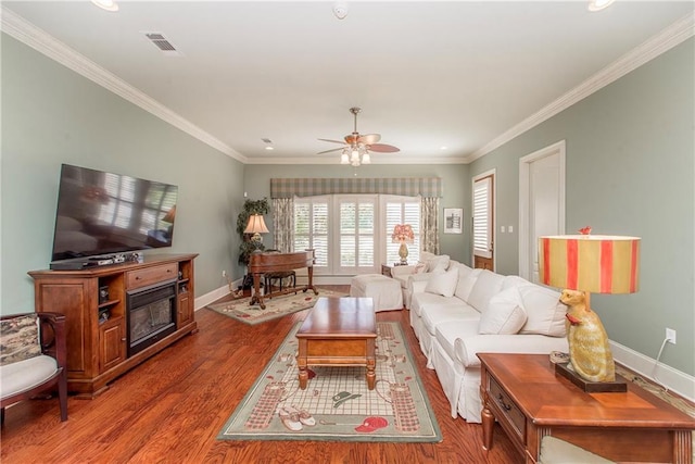23783 Monarch Pt, Springfield, LA 70462 - living area featuring wood finished floors, ceiling fan, baseboards, ornamental molding, and a glass covered fireplace