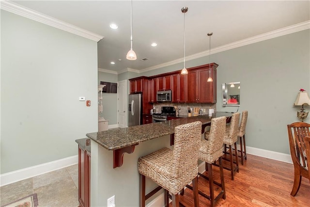 23783 Monarch Pt, Springfield, LA 70462 - kitchen with appliances with stainless steel finishes, tasteful backsplash, a peninsula, reddish brown cabinets, and baseboards