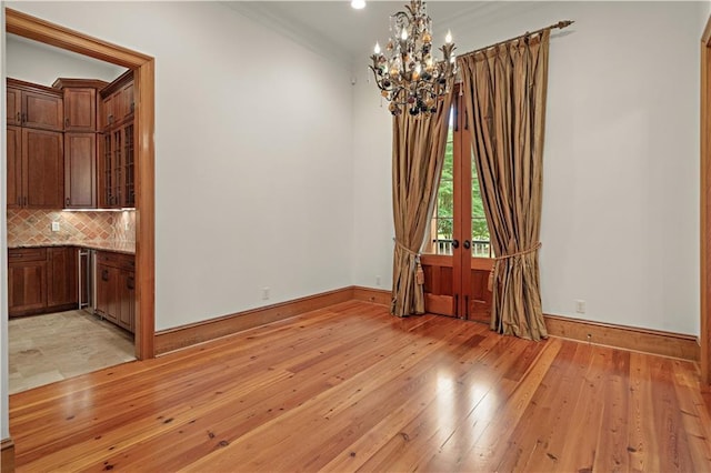 580 Northwoods Dr, Abita Springs, LA 70420 - spare room featuring a chandelier, french doors, light wood finished floors, baseboards, and crown molding