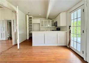 110 Mulberry Ave, Mandeville, LA 70448 - kitchen with white cabinets, light wood-type flooring, stainless steel microwave, glass insert cabinets, and a peninsula
