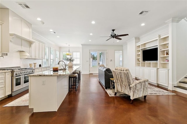 1516 Huron Ave, Metairie, LA 70005 - kitchen with range with two ovens, finished concrete floors, a ceiling fan, an island with sink, and crown molding