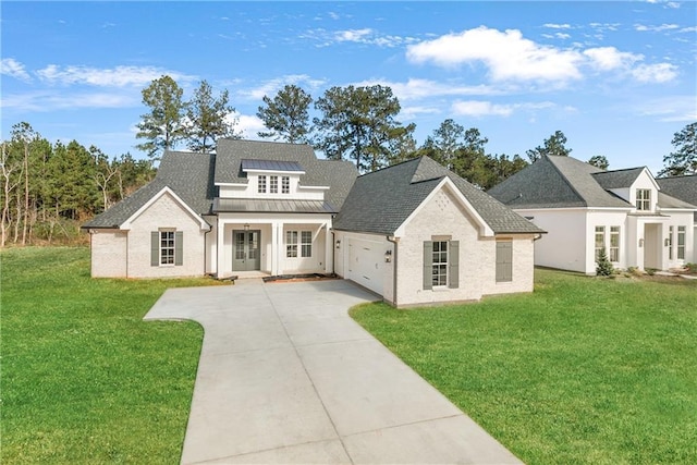 391 Rue Charlotte St, Madisonville, LA 70447 - view of front of home featuring french doors, concrete driveway, a front lawn, a standing seam roof, and an attached garage
