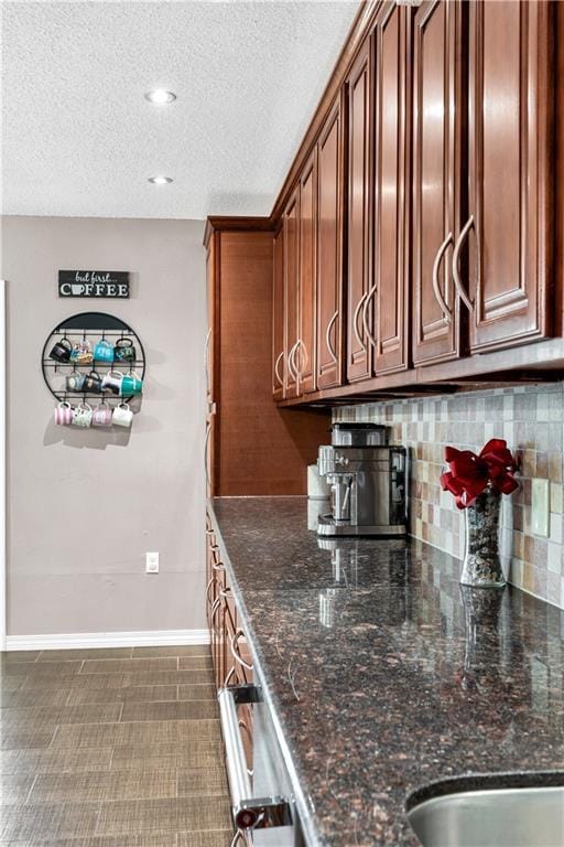 3140 Arbutus Ln, Marrero, LA 70072 - kitchen featuring decorative backsplash, dark stone counters, baseboards, and a textured ceiling