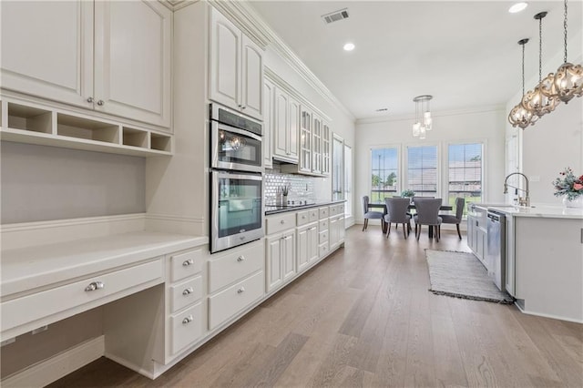 108 Parkview Dr, La Place, LA 70068 - kitchen featuring light wood-style flooring, stainless steel appliances, pendant lighting, white cabinets, and crown molding