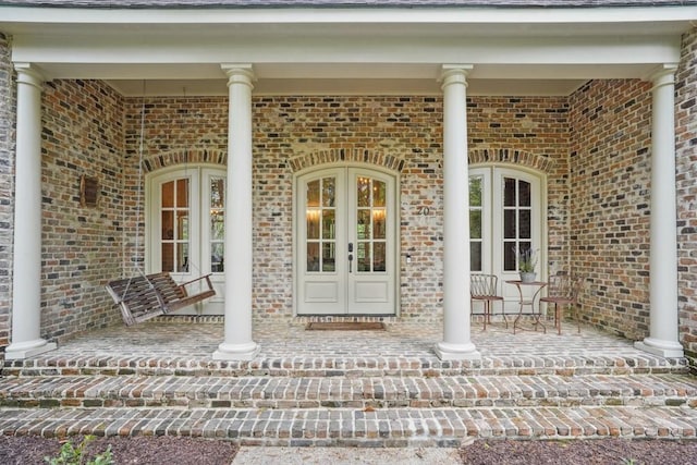 20 Beechwood Gardens Ln, Covington, LA 70435 - doorway to property featuring a porch, brick siding, and french doors