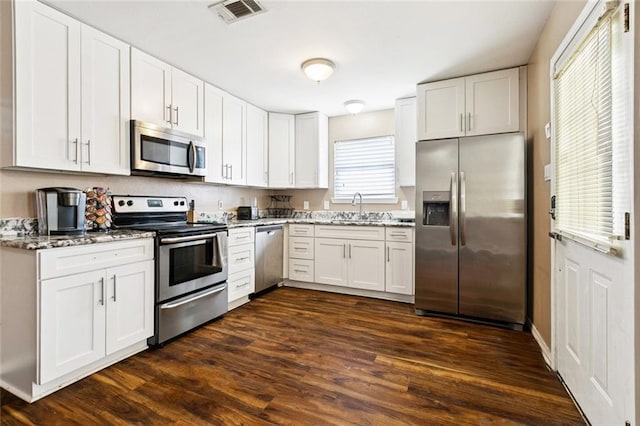 1925 Casa Calvo St, New Orleans, LA 70114 - kitchen with appliances with stainless steel finishes, a sink, light stone counters, dark wood-type flooring, and white cabinets