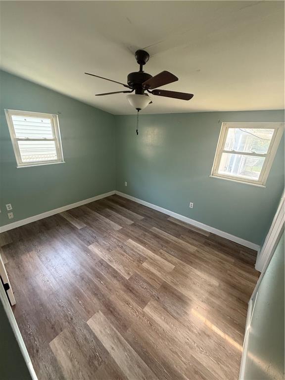 245 W Tish Dr, Avondale, LA 70094 - empty room with plenty of natural light, ceiling fan, wood finished floors, baseboards, and vaulted ceiling