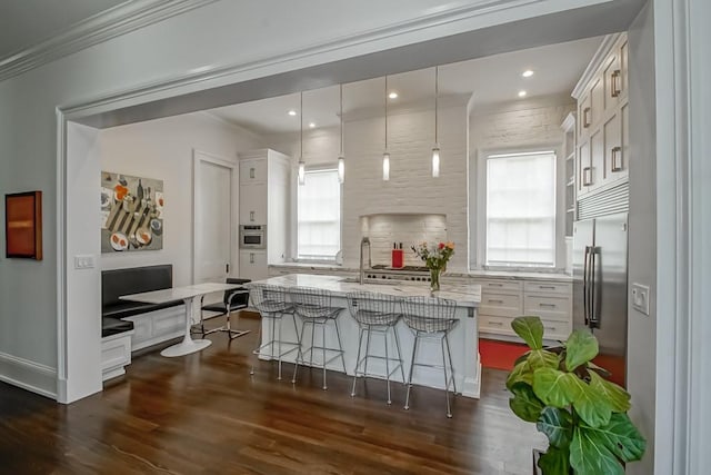 1456 Camp St, New Orleans, LA 70130 - kitchen featuring a breakfast bar, dark wood finished floors, decorative light fixtures, white cabinets, and light stone countertops