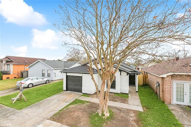 1938 W Homestead Dr, New Orleans, LA 70114 - view of front facade with a front yard, driveway, brick siding, french doors, and a residential view