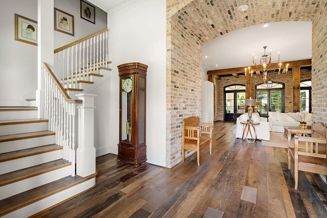 26 Hummingbird Rd, Covington, LA 70433 - foyer entrance featuring hardwood / wood-style flooring, stairs, brick wall, a towering ceiling, and a chandelier