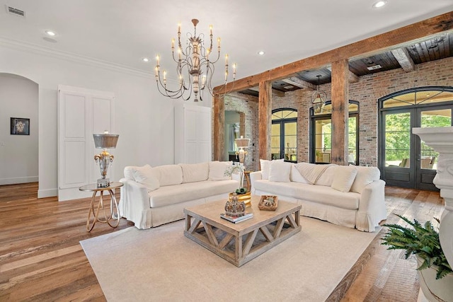 26 Hummingbird Rd, Covington, LA 70433 - living area featuring brick wall, arched walkways, beam ceiling, wood finished floors, and baseboards
