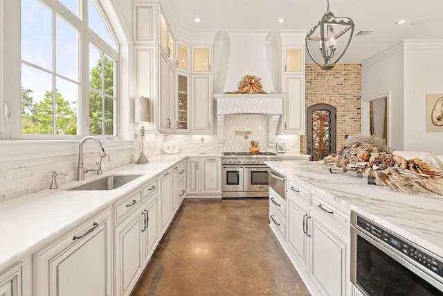 26 Hummingbird Rd, Covington, LA 70433 - kitchen with double oven range, a sink, finished concrete flooring, decorative backsplash, and a chandelier