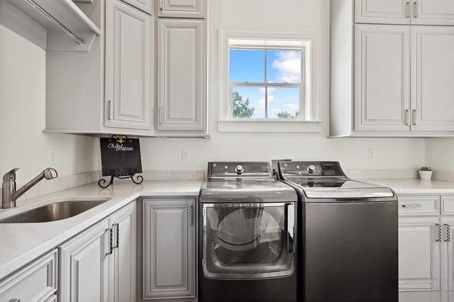 26 Hummingbird Rd, Covington, LA 70433 - laundry area featuring cabinet space and independent washer and dryer