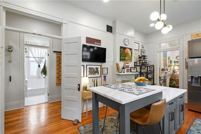 155 Alix St, New Orleans, LA 70114 - kitchen featuring gray cabinetry, stainless steel refrigerator with ice dispenser, light wood-style flooring, a chandelier, and light countertops